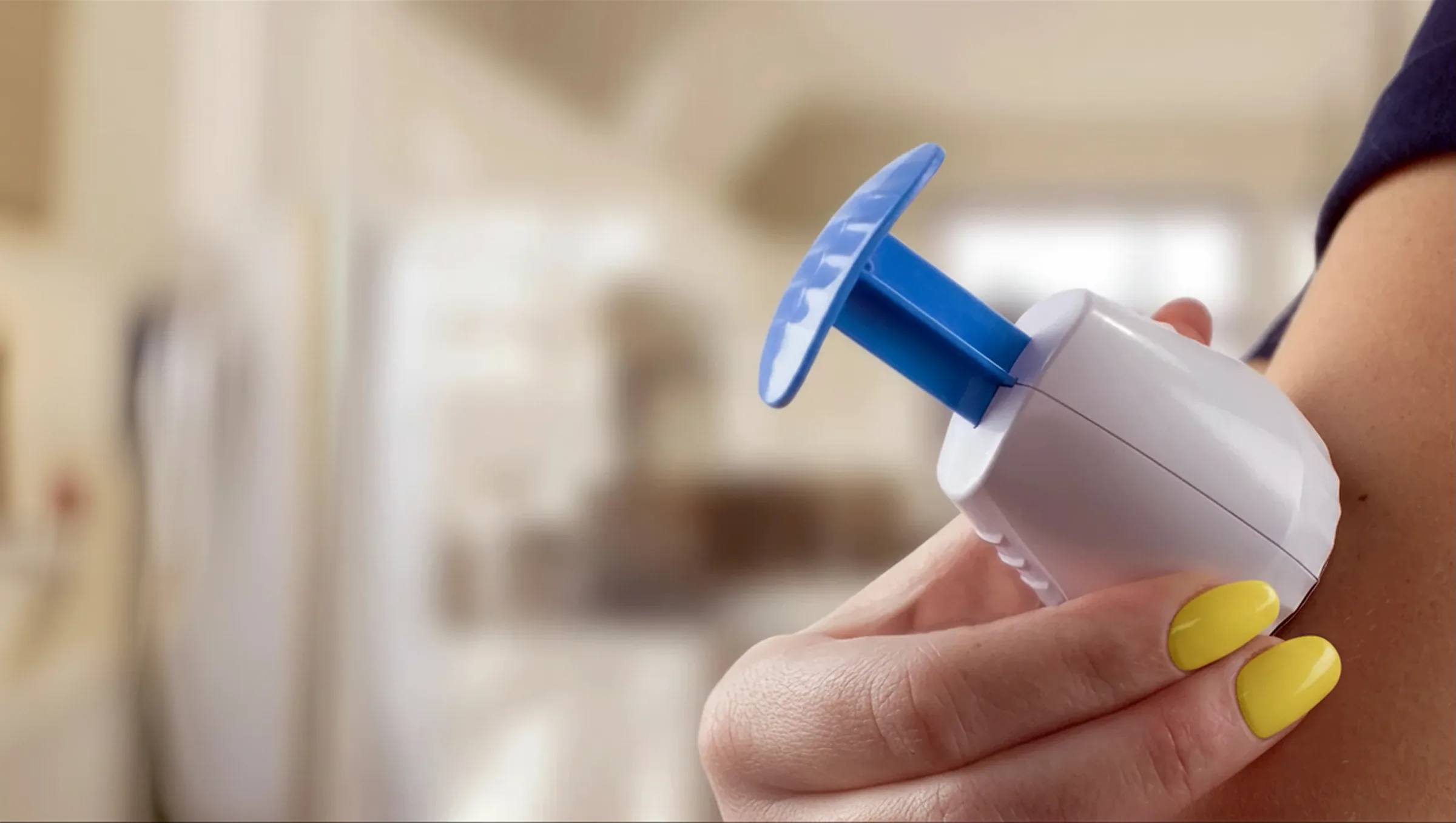 A person collecting a capillary blood sample at home by pressing the YourBio TAP Micro Select to their upper arm